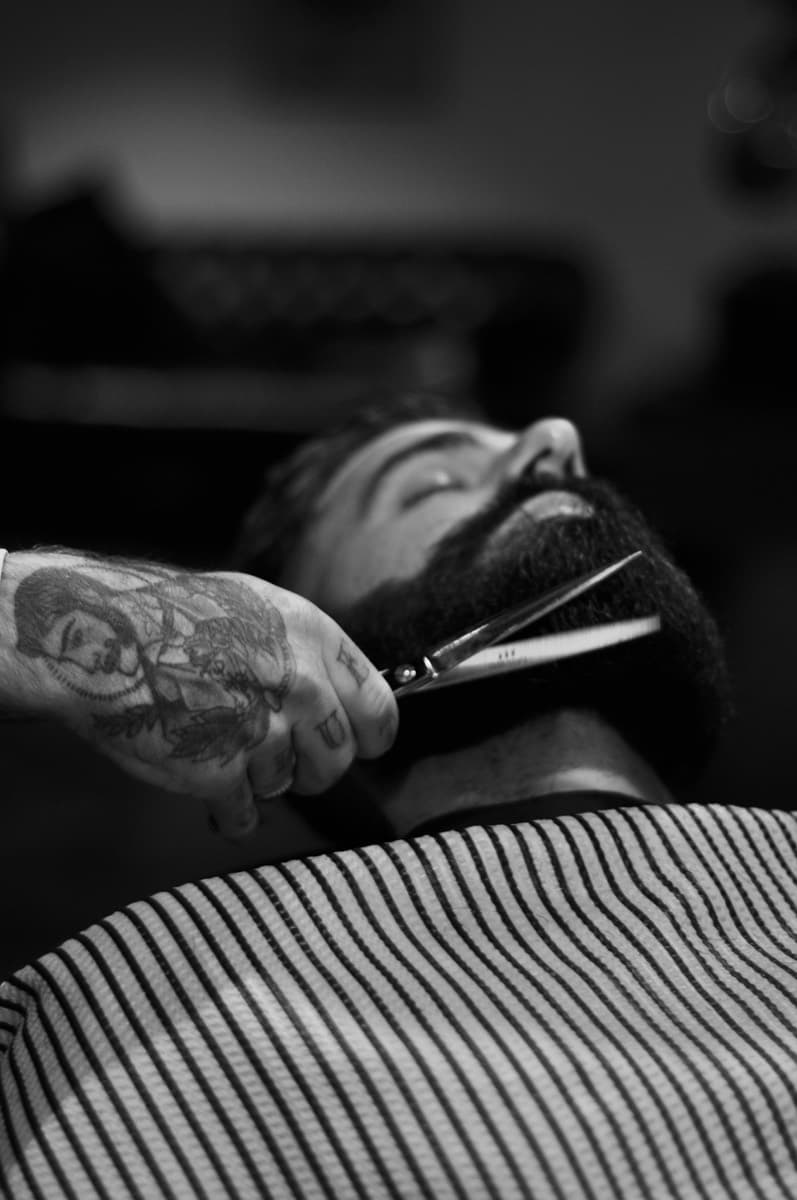 Barber trimming a beard with shears